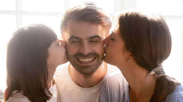 Piccola figlia e madre baciare felice padre marito sulle guance — Foto Stock