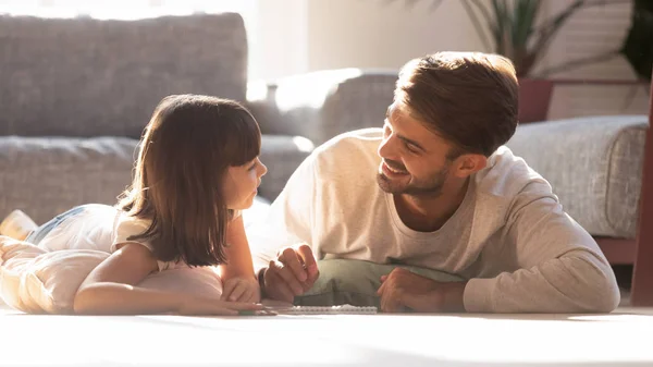 Счастливый отец играет с маленькой дочкой на полу дома — стоковое фото