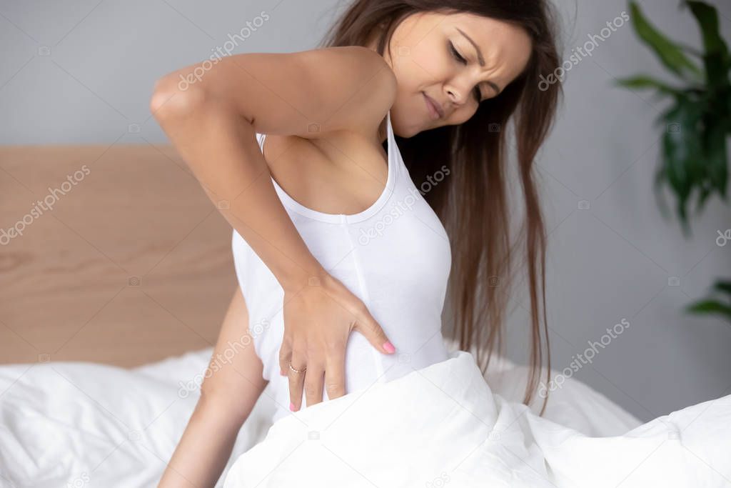 Hurt young woman massage back after bad sleep