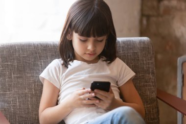 Cep telefonu uygulamaları kullanan sevimli küçük kız, ekrana bakıyor.