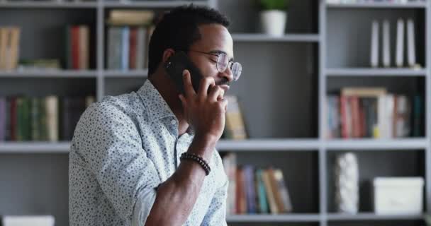 Feliz homem de negócios afro-americano milenar falando ao telefone no escritório — Vídeo de Stock