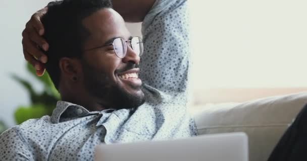 Felice uomo africano soddisfatto rilassarsi con il computer portatile guardando altrove sognando — Video Stock