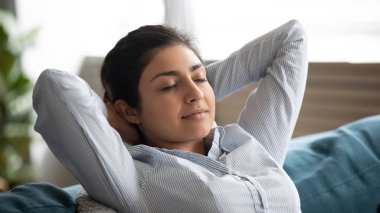 Huzurlu Hintli kadın rahat kanepede dinleniyor. Eller başının arkasında.