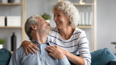 Sevgi dolu eş, sevgili gri saçlı kocaya arkadan sarılıyor.
