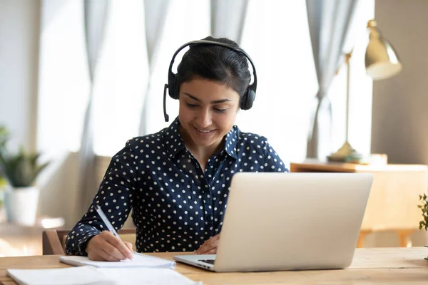 Indian girl student wear headset study online teacher write notes — Stock Photo, Image