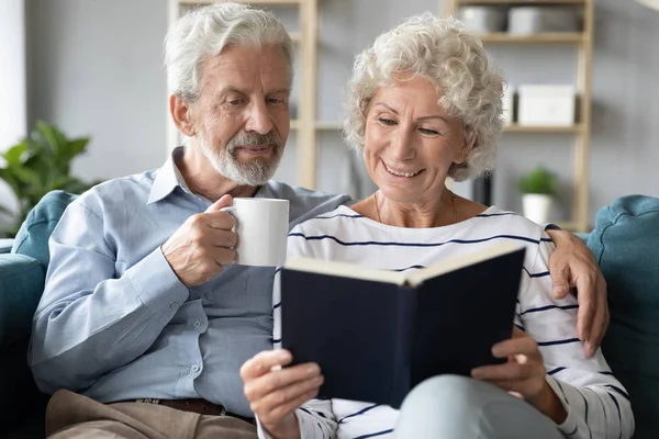 65 'lik eşler evde dinlenip kitap okuyarak içki içiyorlar. — Stok fotoğraf