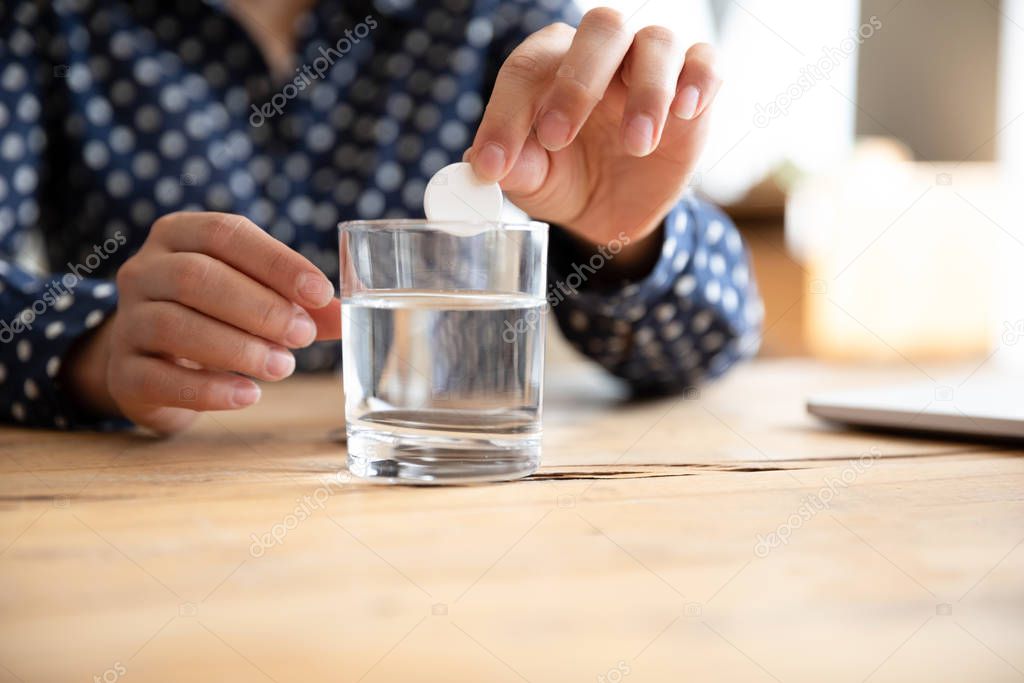 Sick woman drop effervescent aspirin into water glass take medicine