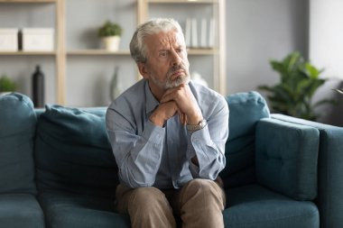 50 'li yaşlarda koltukta oturan yaşlı adam kendini yalnız hissediyor.