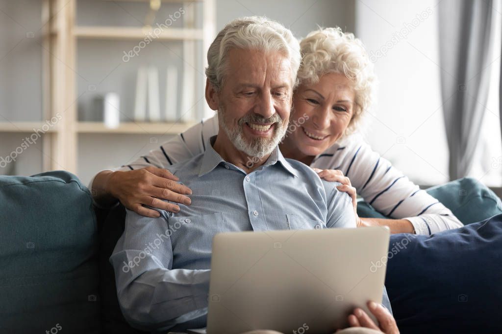 Elderly couple using laptop enjoy virtual entertainment