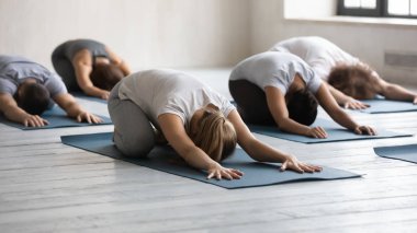 Çeşitli insanlar grup dersinde çocuk egzersizi yapıyor, yoga yapıyorlar.