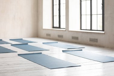 Boş spor salonundaki ahşap zeminde açılmış yoga minderleri.