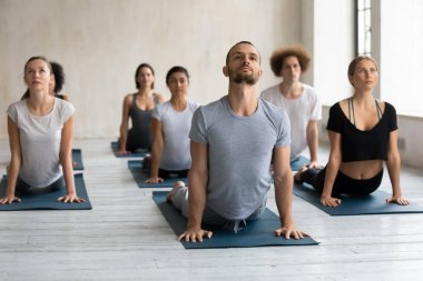Çeşitli insanlar grup dersinde kobra egzersizi yapıyor, yoga yapıyorlar.