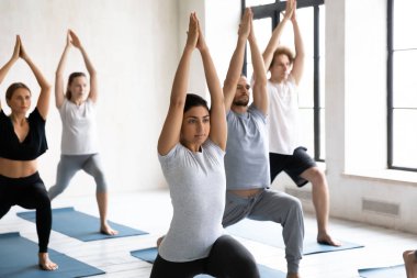 Yoga yapan genç insanlar, Savaşçı 1 egzersizi yapıyorlar.
