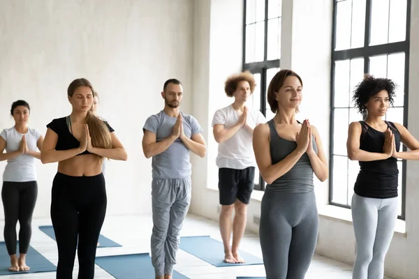 Diverse people practicing yoga, holding hands in namaste gesture — Stock Photo, Image