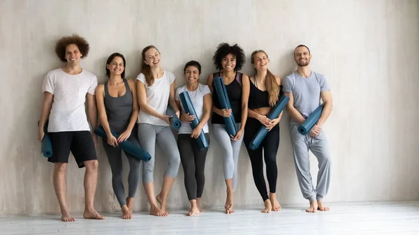 站在瑜伽工作室里，用瑜伽垫向不同的人微笑 — 图库照片