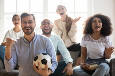 Heyecanlı çok ırklı gençler online futbol izleyen takımı destekliyor.