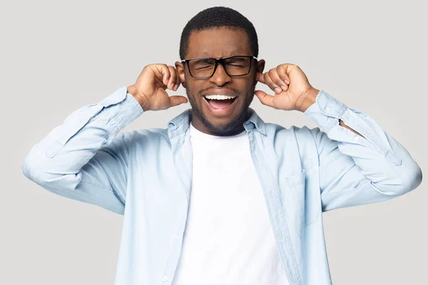 African guy shouting plugging his ears feels annoyed studio shot — Stock Photo, Image