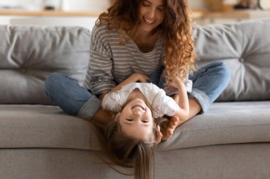 Evdeki kanepede oturan kızıyla oynayan komik bir anne.