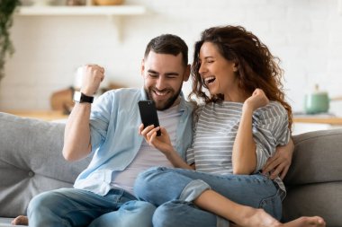 Heyecanlı çift ellerinde akıllı telefonla online piyangoyu kutluyor.