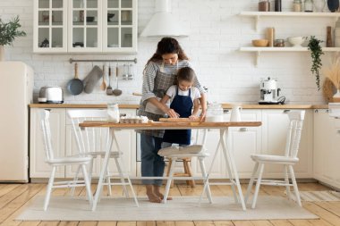 Modern sıcak mutfakta anne ve küçük kız turta hazırlıyorlar.