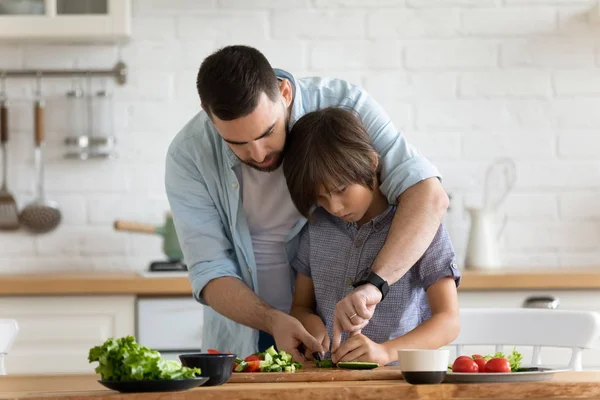 Pai carinhoso ensina seu filho a cozinhar salada de legumes — Fotografia de Stock