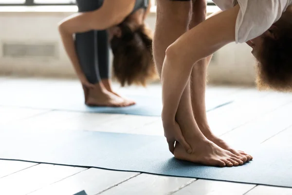 Primer plano personas estirándose en postura uttanasana, practicando yoga —  Fotos de Stock