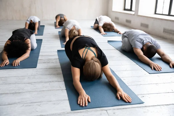 Diversas personas practicando yoga en clase de grupo, haciendo ejercicio Balasana —  Fotos de Stock