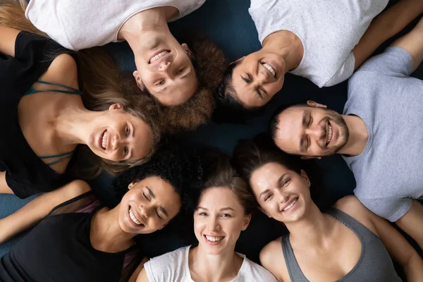 Visão superior sorrindo diversas pessoas deitadas em círculo em tapetes — Fotografia de Stock