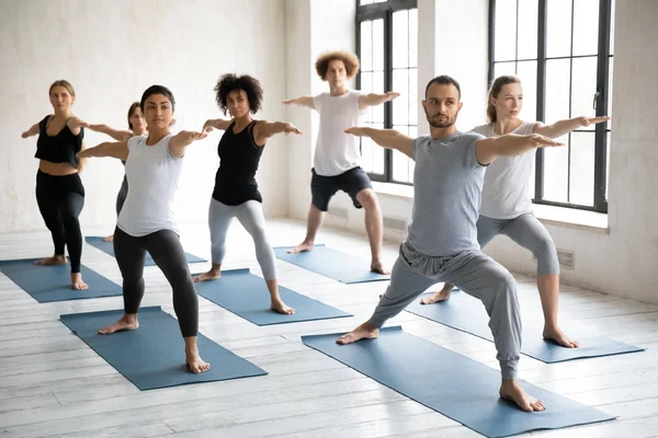 Młodzi, zróżnicowani ludzie ćwiczą na zajęciach jogi grupowej — Zdjęcie stockowe