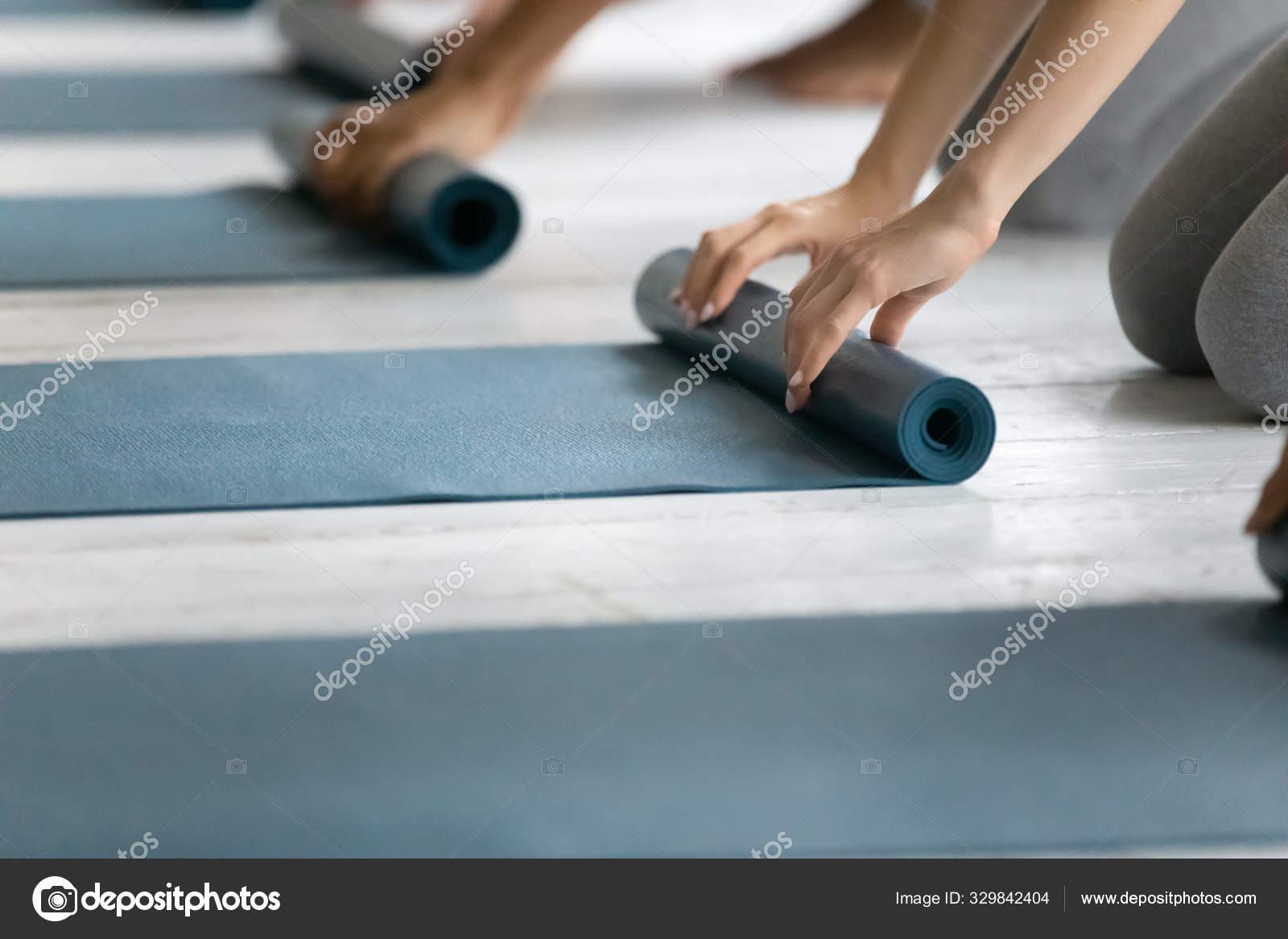 People Folding Yoga Mat After Working Out In Studio Stock Photo