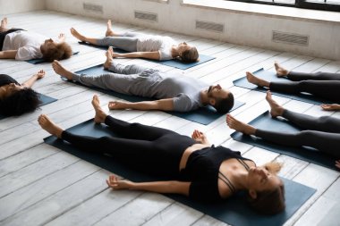 Gençler Savasana 'da meditasyon yapıyor, derste yoga yapıyor.