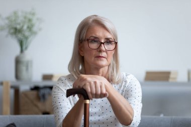 Üzgün yaşlı kadın kendini evde yalnız hisseden bastonu tut.