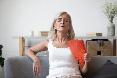 Aşırı ısınmış yaşlı kadın evde el sallıyor.