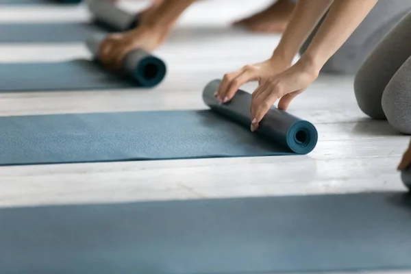 Persone pieghevole tappetino yoga dopo aver lavorato in studio — Foto Stock