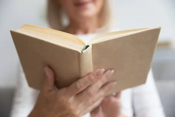 Крупный план зрелой женщины, читающей интересную книгу дома — стоковое фото