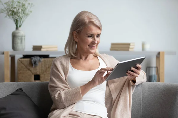 高齢女性は電子タブレットを使用して自宅でリラックス — ストック写真