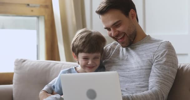Divertido lindo niño hijo aprendiendo usando portátil riendo con papá — Vídeos de Stock