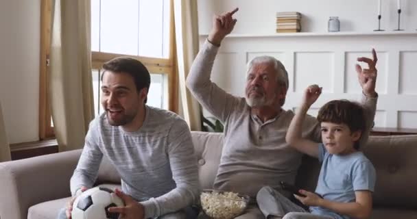 Spännande tre generationer män familj titta på fotbollsmatch fira mål — Stockvideo