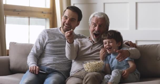Feliz tres generaciones los hombres de la familia tienen control remoto ver tv — Vídeo de stock