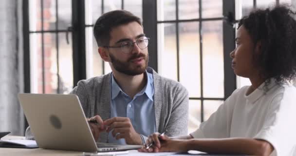 Arkadaş canlısı genç meslekdaşlar konuşuyor. Çalışma masasında oturuyorlar. — Stok video