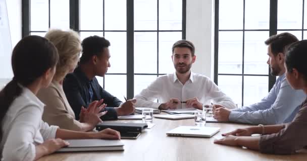 多人種間のビジネスマンは、男性の上司と通信会議テーブルに座る — ストック動画