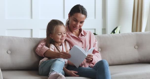 Cuidar madre niñera abrazo preescolar hija lectura libro en casa — Vídeos de Stock