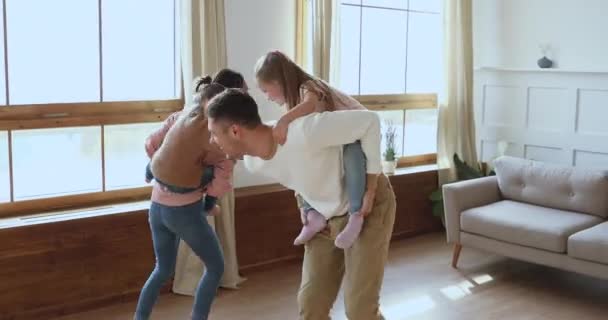 Happy active family parents piggyback children playing in living room — Stock Video