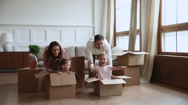 Родители и дети домовладельцы играют с коробками в день переезда — стоковое видео
