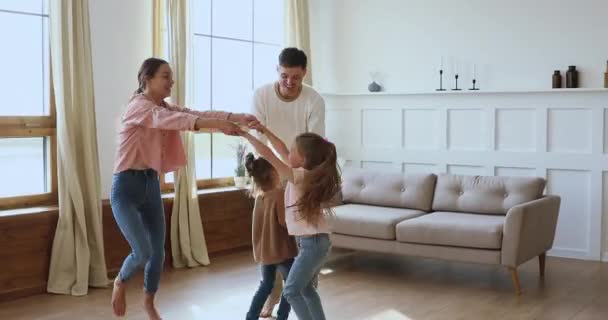 Счастливые родители и дети дочери танцуют прыгая вместе дома — стоковое видео