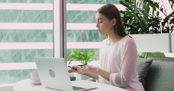 Junge Geschäftsfrau sitzt am Schreibtisch mit Laptop und schreibt Notizen — Stockvideo