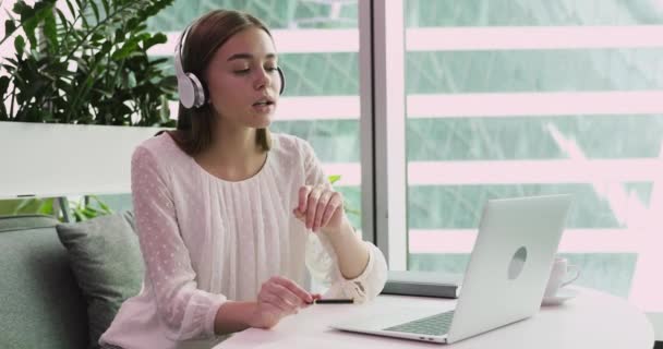 Молодая деловая женщина носит наушники видеоконференции на ноутбуке — стоковое видео