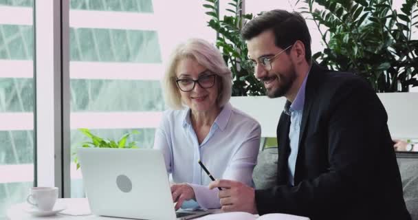 Zwei glückliche junge und alte Kollegen diskutieren Online-Ergebnisse — Stockvideo