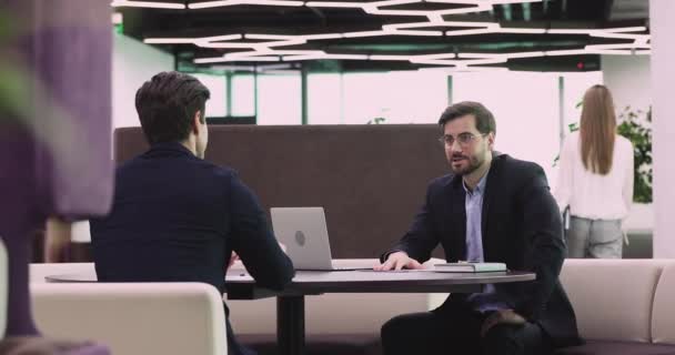 Dua mitra bisnis yang bahagia memakai jas bernegosiasi jabat tangan di kantor — Stok Video