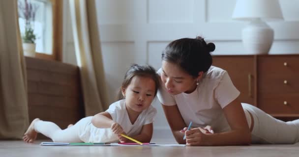 Söt asiatisk flicka rita på varmt golv med mamma — Stockvideo